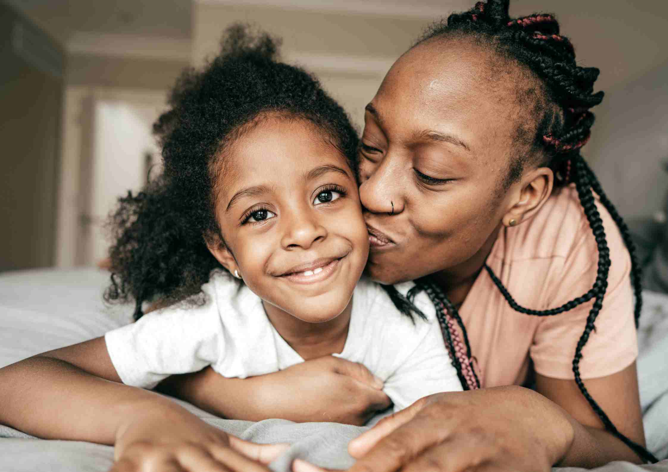mum kissing little girl happy
