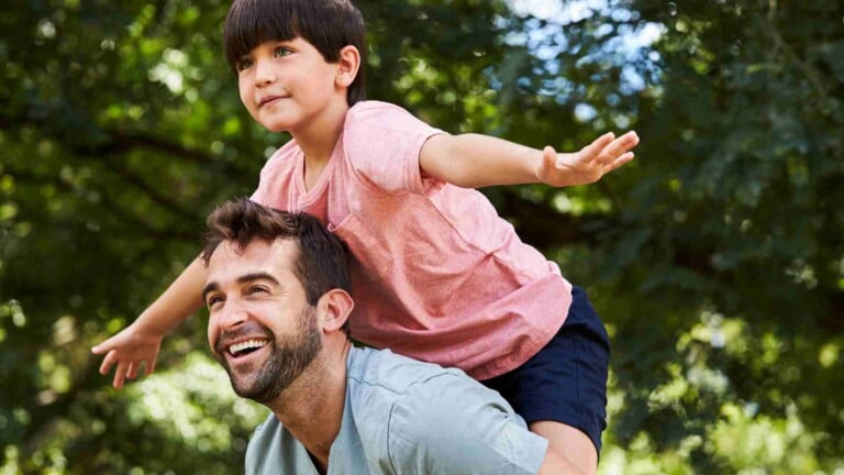 child having fun riding on dad's back outdoors