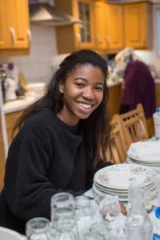 A happy autistic teenage girl sitting at her kitchen table
