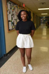 a teenage girl posing for a photo in a school corridor