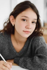 A teenage girl writing at a desk.