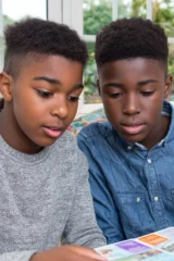 Two boys aged 11 and 12 reading together at home.