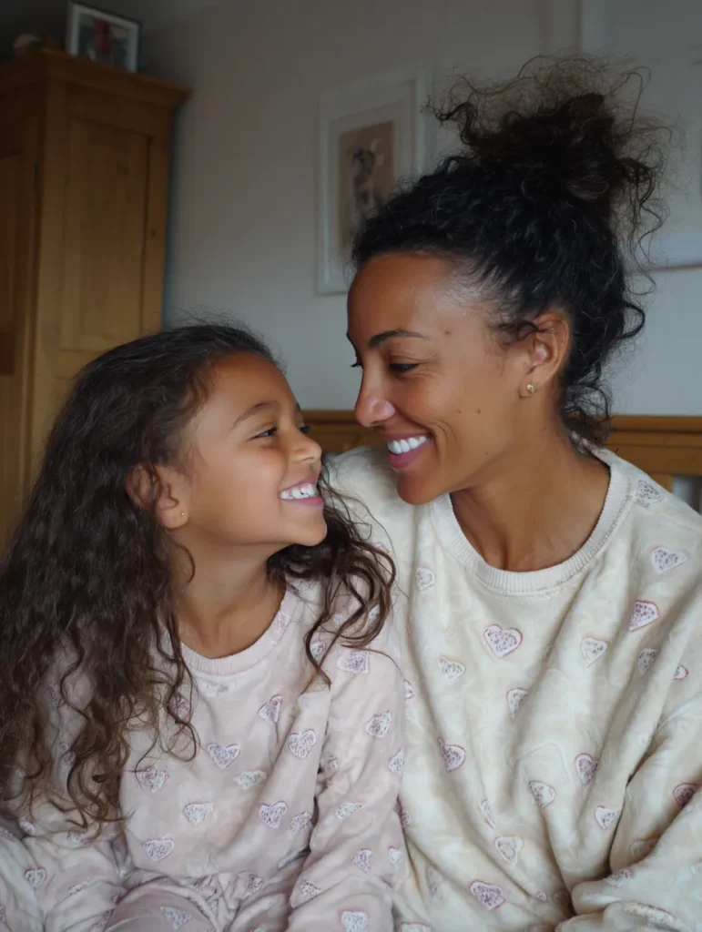 a mother and daughter wearing loungewear snuggled up together and smiling
