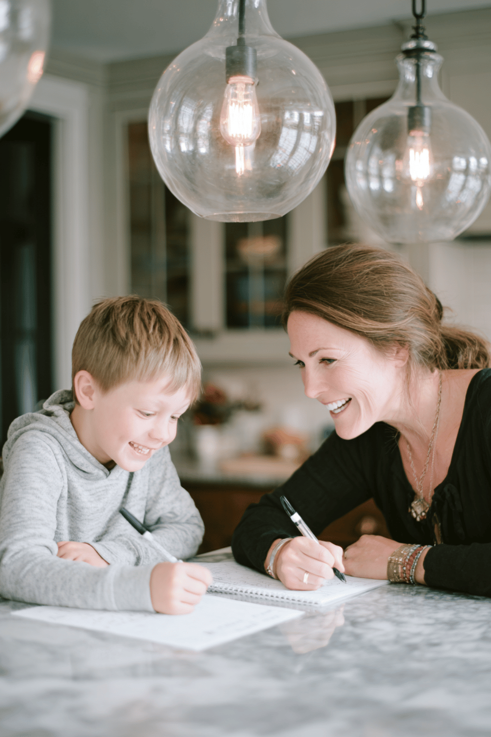 a boy and his mother at their kitchen table writing and chatting