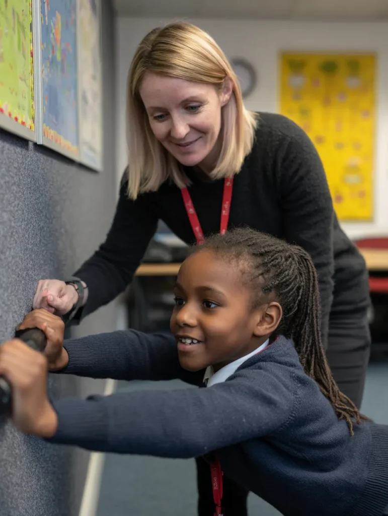 a child taking a movement break in class, supported by her teacher