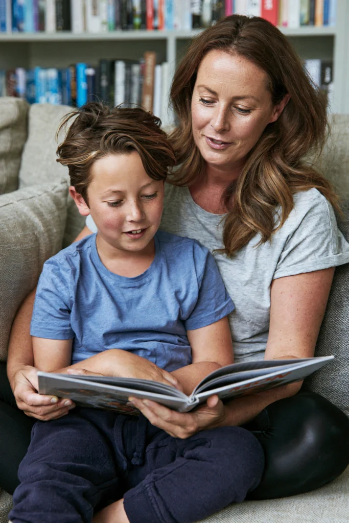 A mother and an eight-year-old boy reading together at home