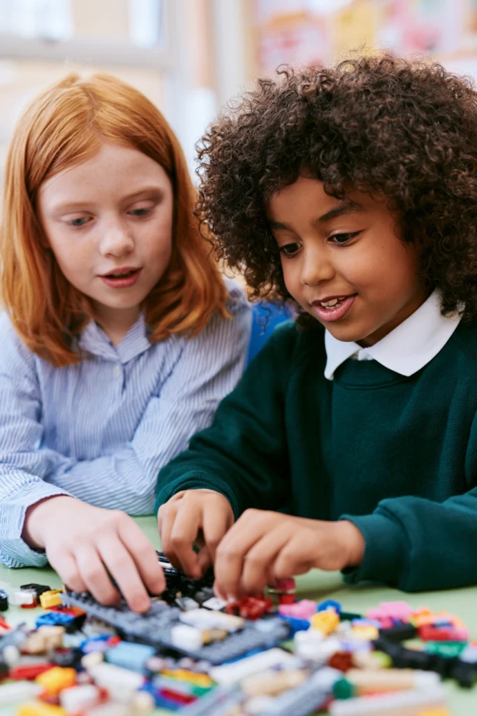 Two 8-year-old school children building Lego together